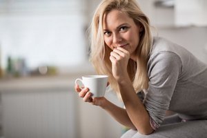 Blonde woman with a side parting holding a cup of coffee